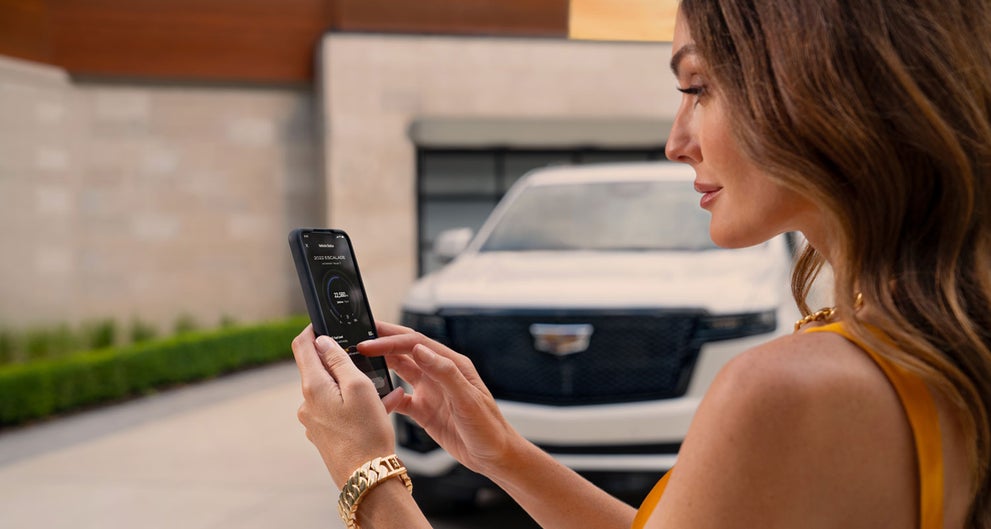 lady checking her mobile with a Cadillac vehicle background | Trapp Cadillac in Houma LA